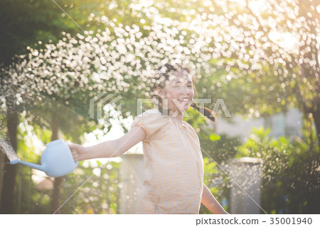 girl watering in the garden on summer day girl watering in the garden on summer day 35001940
