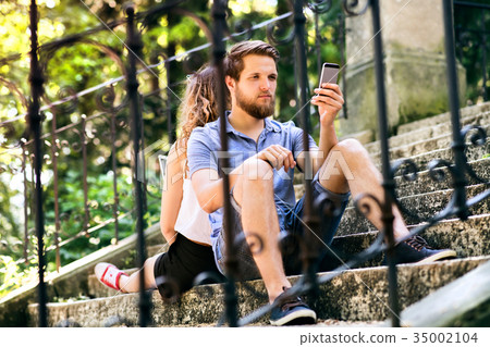Young couple with smartphones sitting on stairs in 35002104