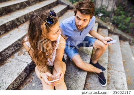 Young couple with smartphones sitting on stairs in Young couple with smartphones sitting on stairs in 35002117