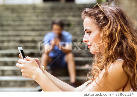 Young couple with smartphones sitting on stairs in Young couple with smartphones sitting on stairs in 35002134