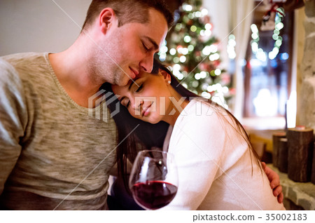 Couple sitting in front of fireplace, drinking 35002183