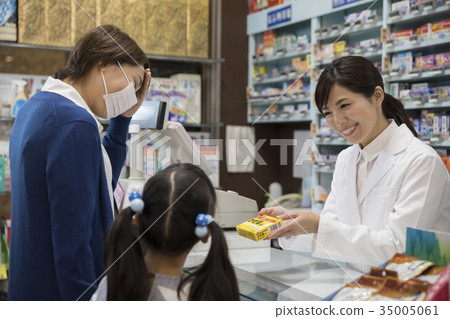 Parents and children buying cold medicine at pharmacy 35005061