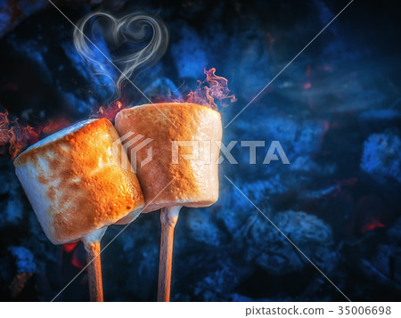 Two brown sweet marshmallows roasting over fire 35006698