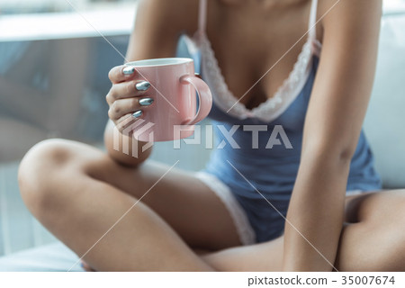 Female hand holding mug of beverage 35007674