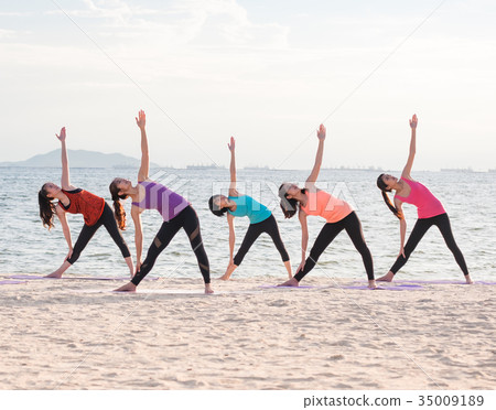 Yoga class at sea beach in evening doing Triangle Yoga class at sea beach in evening doing Triangle 35009189