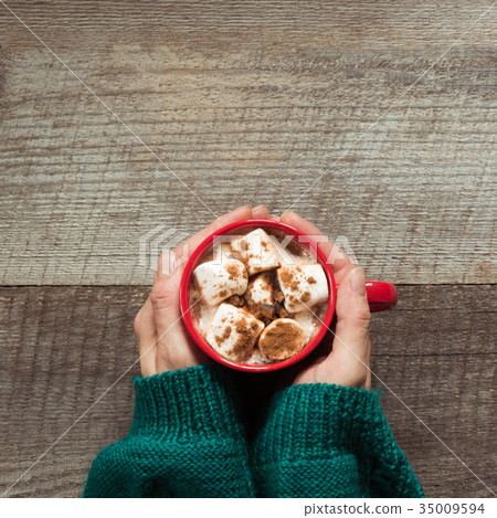 Hot chocolate with marshmallows in hand on board. Hot chocolate with marshmallows in hand on board. 35009594