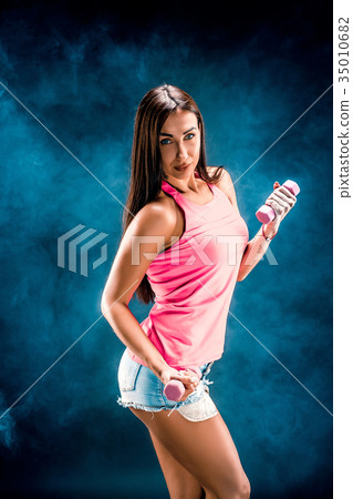Sporty caucasian woman posing with dumbbells in 35010682