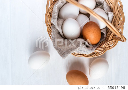 Basket with white and brown natural eggs on white Basket with white and brown natural eggs on white 35012496