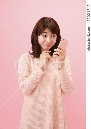 Woman holding a smartphone Pink back Woman holding a smartphone Pink back 35021745