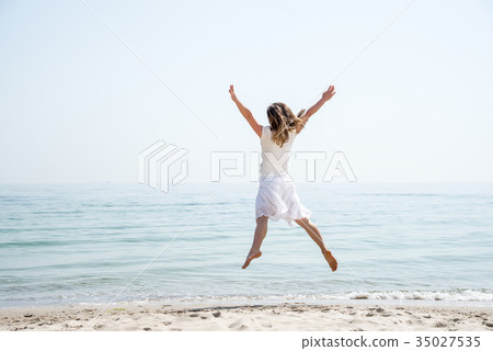Happy beautiful young girl jumping Happy beautiful young girl jumping 35027535