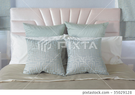 Pastel pillows setting on bed with satin bedding 35029128