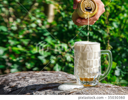 man pouring beer from a jar into a mug 35030360