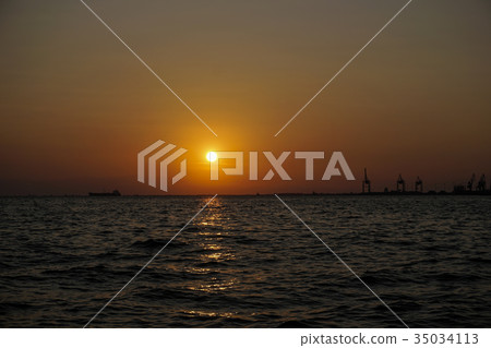 Sea level sunset with ship and port cranes view. 35034113