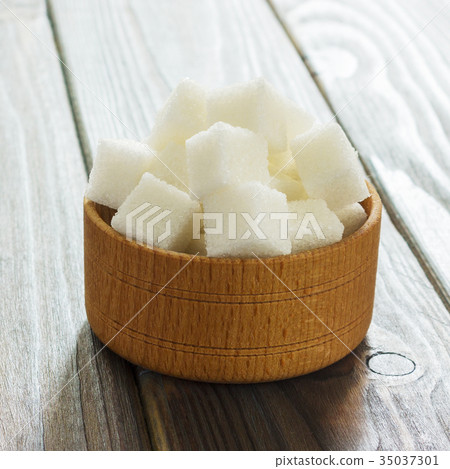 Sugar cubes in bowl on wooden table.  35037301