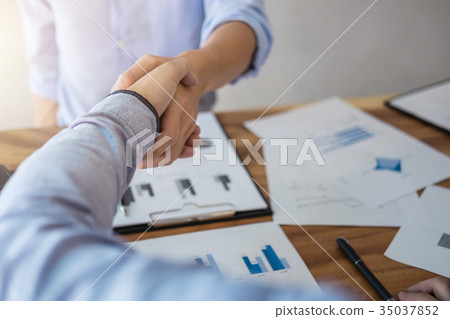 Two smiling businessman shaking hands together after good deal c 35037852