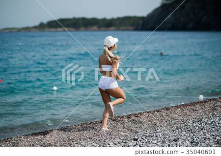 Back view of a blonde girl running against blue 35040601