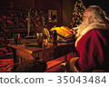 Santa writes naughty/nice list, over shoulder 35043484