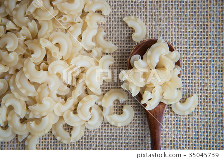 Short, curved and ruffled raw pasta on rustic 35045739