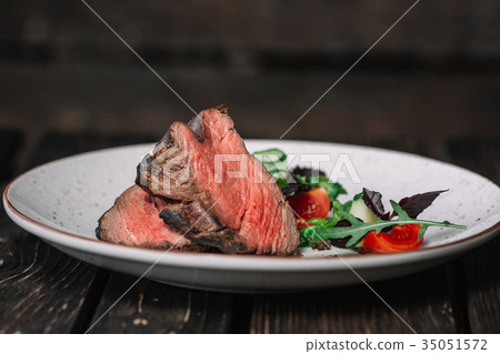Grilled beef steak with salad on dark background Grilled beef steak with salad on dark background 35051572