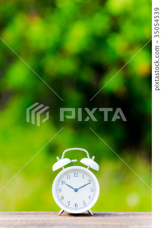 Alarm clock and green blur background Alarm clock and green blur background 35054539