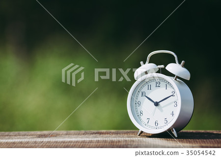 Alarm clock and green blur background Alarm clock and green blur background 35054542