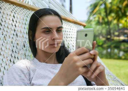 Relaxed young woman looking at mobile phone 35054641