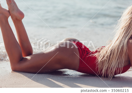 Sexy blonde woman in a red swimsuit lies on the Sexy blonde woman in a red swimsuit lies on the 35060215