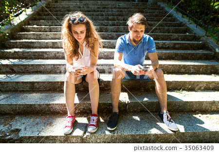 Young couple with smartphones sitting on stairs in 35063409