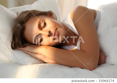 Beautiful young woman sleeping while lying in bed Beautiful young woman sleeping while lying in bed 35068174