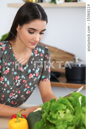 Young hispanic woman or student cooking in kitchen Young hispanic woman or student cooking in kitchen 35068214