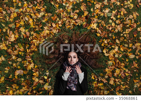 Fall portrait of a girl lying on a lawn in a 35068861
