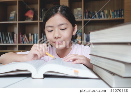 Girl reading and writing in library of school. Girl reading and writing in library of school. 35070588