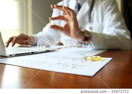 doctor working on a computer at his cabinet. Pills 35071772