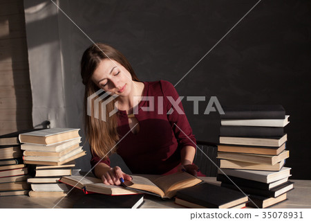 the girl sitting at the table reading a lot of 35078931