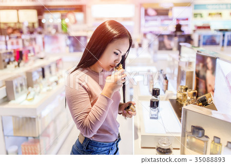 Asian woman testing perfume in duty free store 35088893
