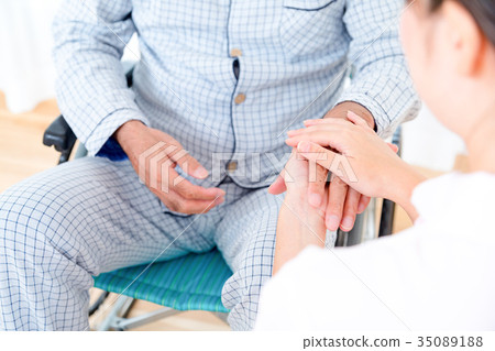 年輕的護士和爺爺牽手手觸摸退休之家日託中心輪椅 35089188
