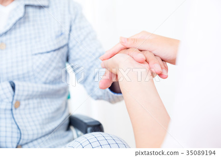 年輕的護士和爺爺牽手手觸摸退休之家日託中心輪椅 年輕的護士和爺爺牽手手觸摸退休之家日託中心輪椅 35089194
