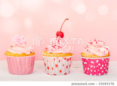 Row of three cupcakes with cream and decorations Row of three cupcakes with cream and decorations 35095576