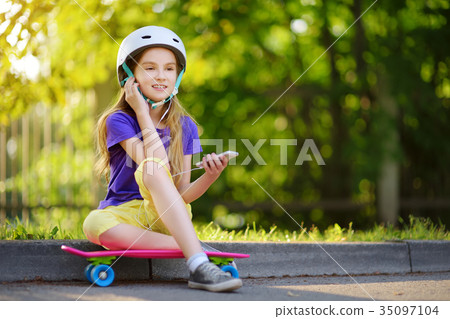 Pretty little girl learning to skateboard on beautiful summer day in a park 35097104
