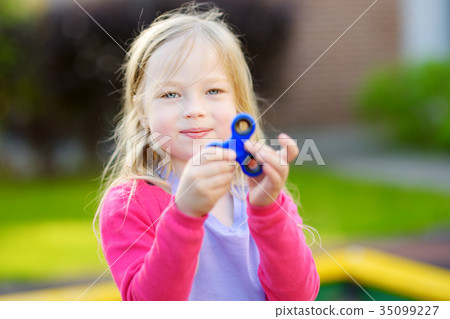 Cute school girl playing with fidget spinner Cute school girl playing with fidget spinner 35099227