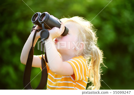 Funny little girl looking through binoculars on sunny summer day Funny little girl looking through binoculars on sunny summer day 35099247