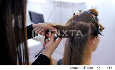 Professional hairdresser doing hairstyle for young 35099511