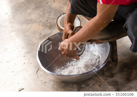 Woman sit on coconut grater and grate coconut Woman sit on coconut grater and grate coconut 35100106