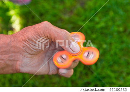 Orange Spinner in the hands of an elderly man 35100283