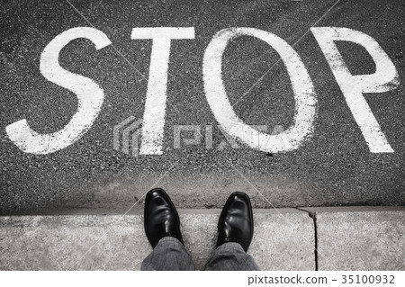 Feet of a man and stop road marking label Feet of a man and stop road marking label 35100932