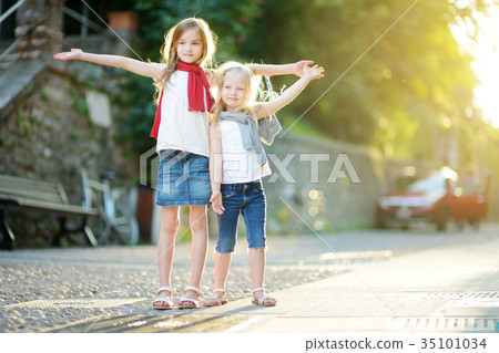 Two adorable little sisters having fun together on warm and sunny summer evening 35101034