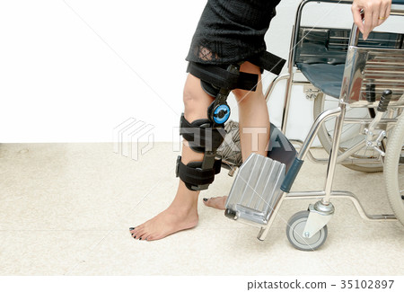 Patient on knee brace support try to walk training 35102897