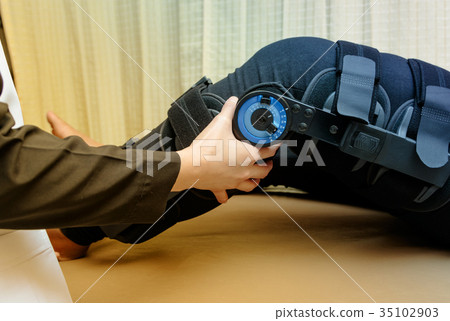 therapist adjust knee braces on patient 's leg  35102903