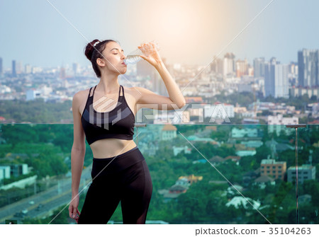 Happy woman in sport clothes drinking water  35104263