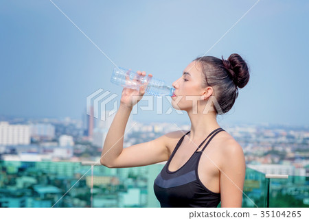 Happy woman in sport clothes drinking water 35104265